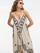 Vestido largo negro con breteles finos y bordado dorado con motivos geométricos. Corte evasé con picos en los laterales.