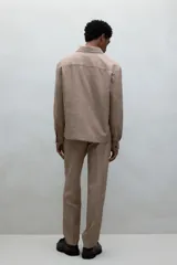 Pantalón de vestir color beige con textura de lino, corte recto, bolsillos laterales y traseros con botón. Cierre con cremallera y botón oculto.