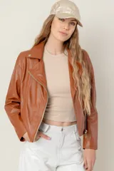 Campera estilo motociclista de cuero color marrón caramelo, con cuello solapa, cierre asimétrico plateado y detalles de broches metálicos.