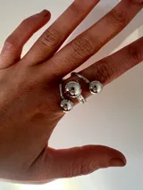 Anillo plateado regulable con tres bolas decorativas.