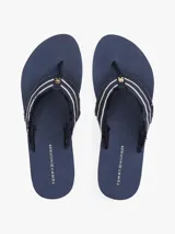 Ojotas Tommy Hilfiger azul marino con tiras de tela trenzada con rayas blancas y suela plana.