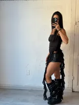 Vestido corto negro sin mangas, con escote recto y falda asimétrica con volados de encaje.