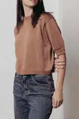 Sweater color dorado de tejido de punto suave con hilos metalizados, corte recto y mangas cortas con puño ajustado.