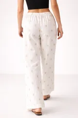Pantalón de algodón blanco con bordado tipo broderie de flores, de corte holgado y tiro alto.