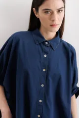 Camisa azul de mangas cortas abullonadas, con cuello clásico y cierre frontal con botones.