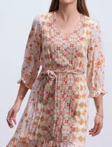 Vestido midi estampado con flores y mandalas en tonos naranja, rojo y celeste, con escote en V, mangas 3/4 con puños fruncidos, cintura elastizada con lazo y ruedo irregular.