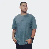 Remera de manga corta, corte oversize, color azul con efecto acid wash o distorsión. Presenta un pequeño texto bordado o estampado en el pecho.