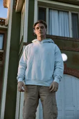 Buzo con capucha celeste, de manga larga y fit loose. Confeccionado en tejido loop back cepillado por dentro, con mangas ranglán, puños de canalé, forro de la misma tela en el interior de la capucha y estampa en goma de tacto suave ubicada en la espalda.