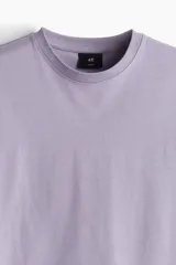 Remera lila de algodón pesado, corte holgado, con cuello redondo ribeteado y hombros caídos.