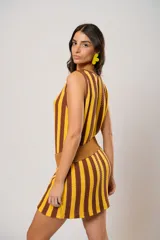 Vestido corto tejido a rayas verticales color amarillo y marrón, con escote redondo y mangas sisa. Incluye cinturón marrón con hebilla dorada.