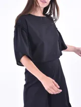 Blusa negra de mangas cortas con volados y escote redondo.