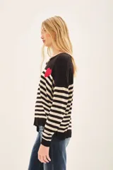 Sweater de punto a rayas horizontales en blanco y negro, con detalle de corazón rojo en el pecho.