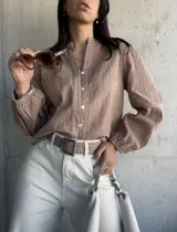 Camisa color beige con bordados florales, cuello mao y mangas largas abullonadas.