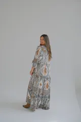 Vestido largo de corte amplio con estampado geométrico en tonos grises, marrones y blancos. Tiene cuello en V y mangas 3/4.