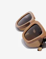 Gafas de sol Hawkers unisex, modelo Uptown, con montura cuadrada color marrón y lentes marrones. Patillas con estampado carey.