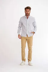 Pantalón de vestir color beige, de corte recto, con bolsillos laterales y traseros. Se ajusta a la cintura con cinturón de cuero marrón.