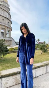 Camisa azul de terciopelo, corte oversize, con cuello camisero, manga larga y cierre frontal con botones.