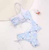 Traje de baño enterizo celeste con estampado de flores blancas, de un solo hombro y con abertura en la cintura.