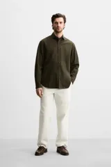 Camisa verde oscuro de corte regular, confeccionada en tejido de mezcla de algodón y lyocell. Tiene cuello italiano, manga larga con puños abotonados y cierre frontal con botones.