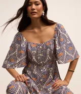 Vestido long midi de viscosa estampada con corazones y piñas, escote corazón, mangas cortas evasé, volado en el ruedo y botones delanteros.