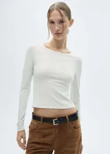 Remera de punto fino color blanco, de manga larga y cuello redondo.