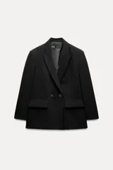 Blazer negra oversize con cuello solapa, manga larga con hombreras, bolsillos delanteros con solapa y cierre frontal cruzado con botones.