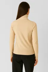 Polera de tejido acrílico color marrón, de manga larga y cuello tortuga.