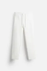 Pantalón de jogging blanco de corte recto, con cintura elástica ajustable con cordón, bolsillos frontales y detalle de bolsillos de vivo en la espalda.