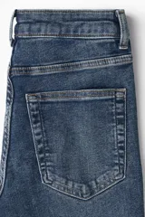 Jean de denim azul con tiro alto, cierre con botón y piernas amplias con bajos acampanados.