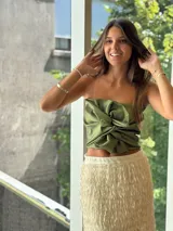 Top strapless color crudo con efecto satinado, caracterizado por un drapeado estructurado y un nudo frontal prominente.