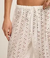 Pantalón de playa blanco con bordado calado tipo laise, cintura elastizada con cordón ajustable y corte recto.