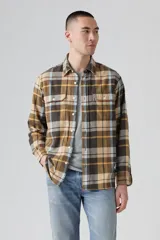 Camisa de manga larga con estampado a cuadros en tonos marrón, beige, celeste y rojo. Tiene cuello clásico, cierre con botones, dos bolsillos con solapa abotonada en el pecho y logo de la marca en el bolsillo izquierdo.