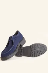 Zapato tipo wallabee de gamuza azul con costuras blancas a la vista y suela de goma negra con plataforma.
