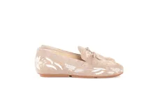 Mocasín de cuero gamuzado color avena, con bordados contrastantes, apliques metálicos y lazo decorativo en la capellada.