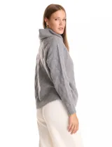 Buzo de punto grueso color beige, con cuello volcado y textura en relieve. Tiene mangas largas de corte hombro caído y puños anchos.