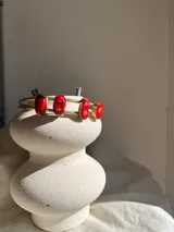 Brazalete rígido de bronce dorado con cuatro piedras de coral rojo incrustadas.
