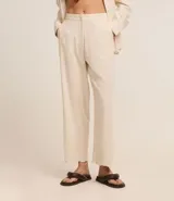 Pantalón recto de cintura alta confeccionado en viscolino color crudo, con elástico en la parte trasera de la cintura, cierre tradicional y textura de palmeras perforadas en el bajo.