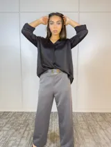 Blusa negra de satén con escote en V y mangas largas con puños abotonados.
