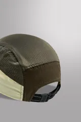 Gorra marrón de siete paneles de tejido técnico con perforaciones, visera y ajuste elástico en la parte posterior.