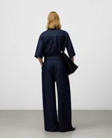 Pantalón de denim azul marino, tiro alto, con pinzas delanteras, canesú trasero y pierna ancha. Incluye cinturón de lazo del mismo tejido.