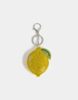 Llavero con dije de limón amarillo cubierto de strass y hoja verde. Incluye mosquetón metálico plateado para colgar en carteras, mochilas o bolsos.
