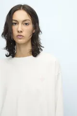 Remera blanca de manga larga con cuello redondo y pequeño logo estampado en el pecho y en la manga.