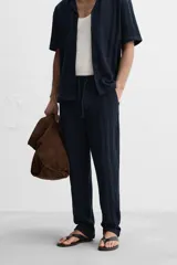 Pantalón azul marino de corte relaxed fit, confeccionado en tejido con mezcla de algodón. Presenta cintura elástica ajustable con cordón, bolsillos frontales y detalle de bolsillo trasero de plastrón.