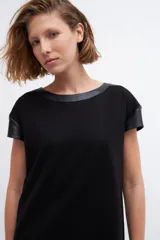 Vestido negro de corte recto y manga corta, con cuello y hombros con apliques de cuero ecológico negro.