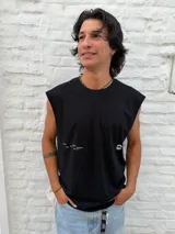 Musculosa negra de corte holgado con hombros caídos, estampado gráfico abstracto en espiral en la espalda con la palabra "OSTEN" arriba y las palabras "DEEP", "ENERGY", "MINDSET", "BALANCE" debajo.