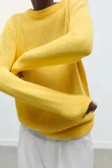 Jersey amarillo de punto rústico, corte recto, cuello redondo y manga larga con terminaciones en rib.