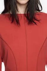 Vestido de largo midi en color negro con corte en línea A y vuelo. Posee escote barco, mangas largas tipo murciélago ajustadas en los puños y detalles de pespuntes decorativos a contraste. Está confeccionado en una mezcla de cupro y elastano.