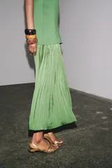 Vestido largo verde con escote redondo y sisas amplias. La parte superior es de punto liso y la falda es plisada de tejido satinado.