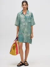 Camisa vestido celeste con efecto tie-dye, de corte oversize, manga corta y cuello camisero. Tiene cierre frontal con botones y un bolsillo en el pecho.
