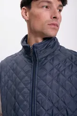 Chaleco azul marino con diseño capitoneado, cuello alto y cierre frontal con cremallera.